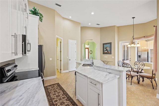 kitchen with appliances with stainless steel finishes, light stone countertops, white cabinets, decorative light fixtures, and sink