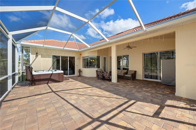 view of patio with a hot tub, an outdoor living space, ceiling fan, and glass enclosure