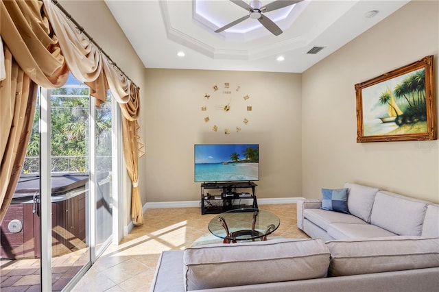 living room featuring light tile patterned floors, ceiling fan, and a raised ceiling