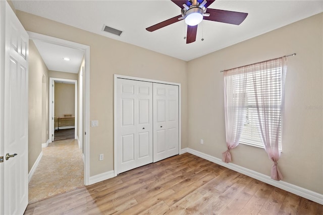 unfurnished bedroom with light hardwood / wood-style flooring, ceiling fan, and a closet