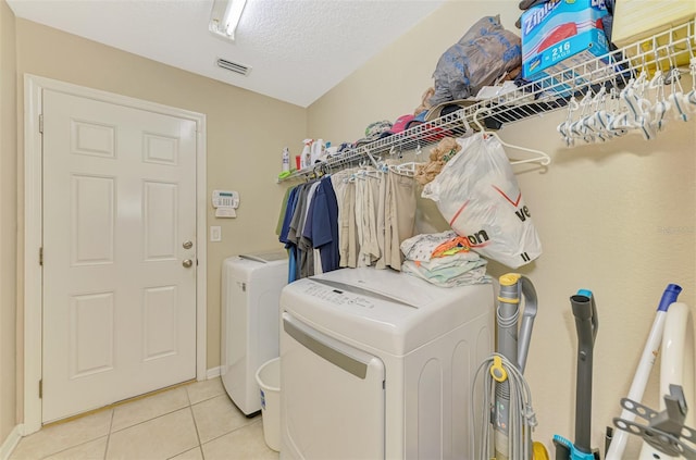 laundry room featuring light tile patterned floors, washer and dryer, and a textured ceiling