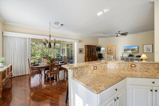 kitchen with white cabinetry, light stone counters, dark wood-type flooring, and hanging light fixtures