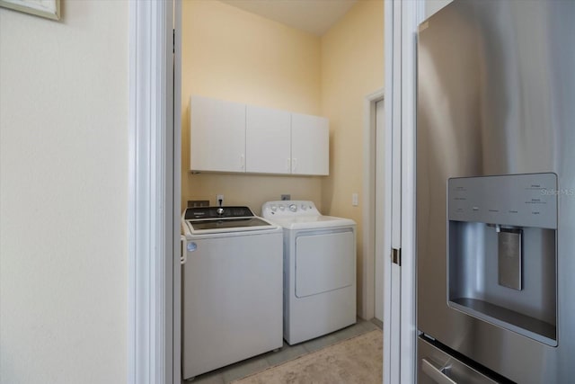 washroom with water heater, light tile patterned flooring, washing machine and clothes dryer, and cabinets