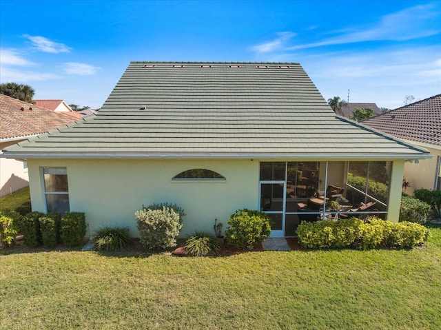 back of property with a sunroom and a lawn