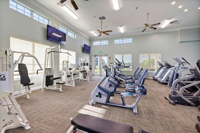 exercise room featuring crown molding, carpet flooring, ceiling fan, and a towering ceiling