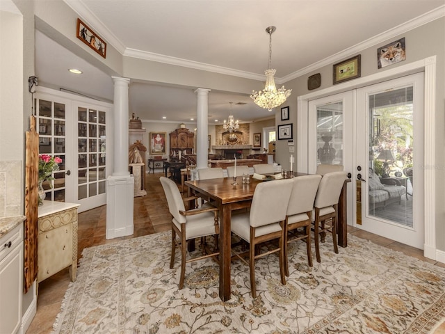 dining area with french doors, ornamental molding, a chandelier, and ornate columns