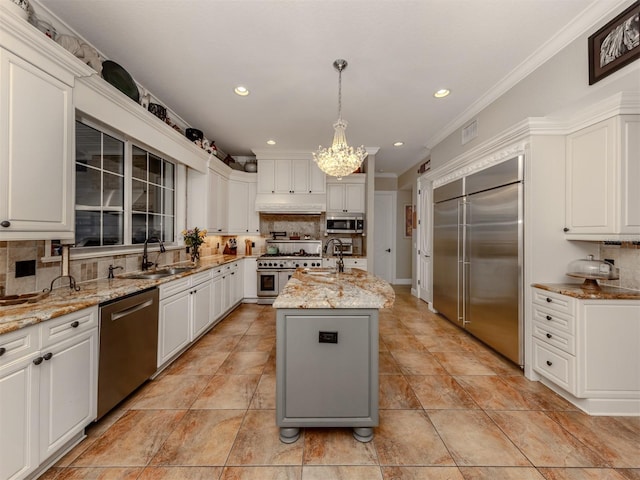 kitchen featuring decorative light fixtures, high quality appliances, sink, a kitchen island with sink, and light stone countertops