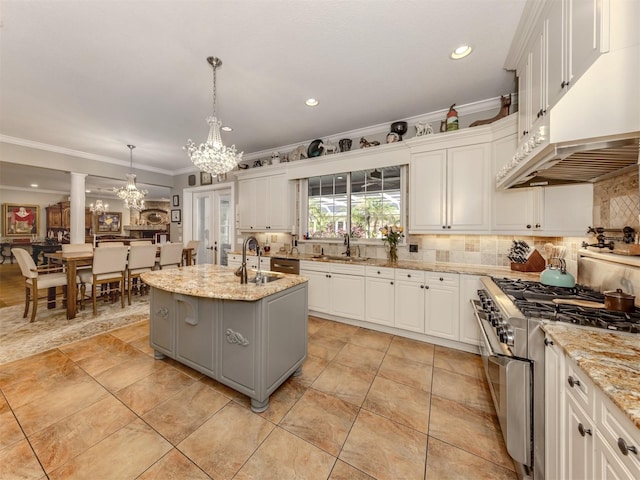 kitchen with white cabinetry, hanging light fixtures, stainless steel range, and an island with sink