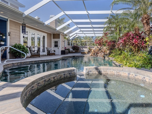 view of swimming pool featuring a patio, an in ground hot tub, french doors, and glass enclosure