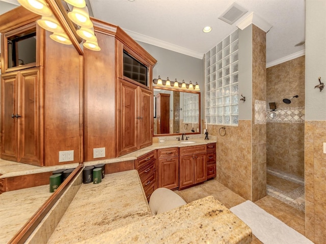 bathroom with vanity, ornamental molding, a tile shower, and tile walls