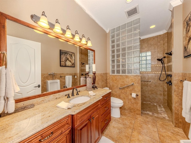 bathroom with tile patterned flooring, tile walls, vanity, a tile shower, and ornamental molding