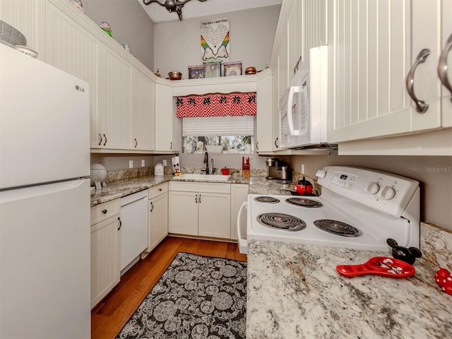 kitchen with sink, light stone counters, light hardwood / wood-style flooring, white appliances, and white cabinets