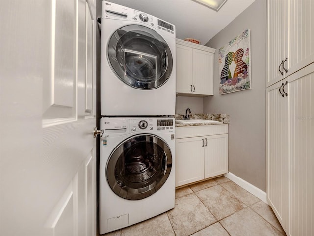 laundry room featuring cabinets, stacked washer / dryer, sink, and light tile patterned floors