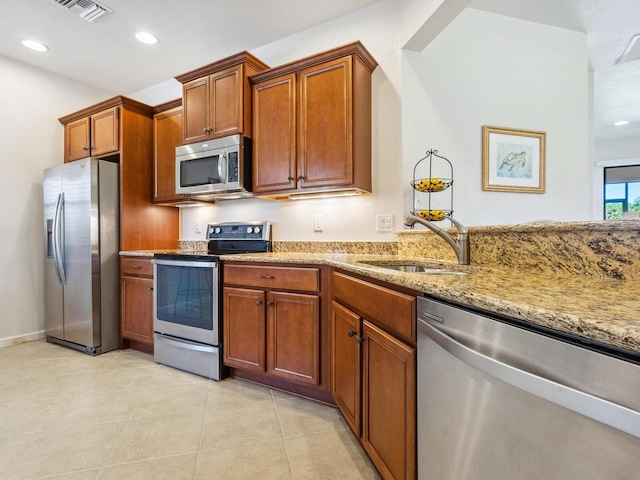 kitchen with stainless steel appliances, sink, light tile patterned floors, and light stone counters