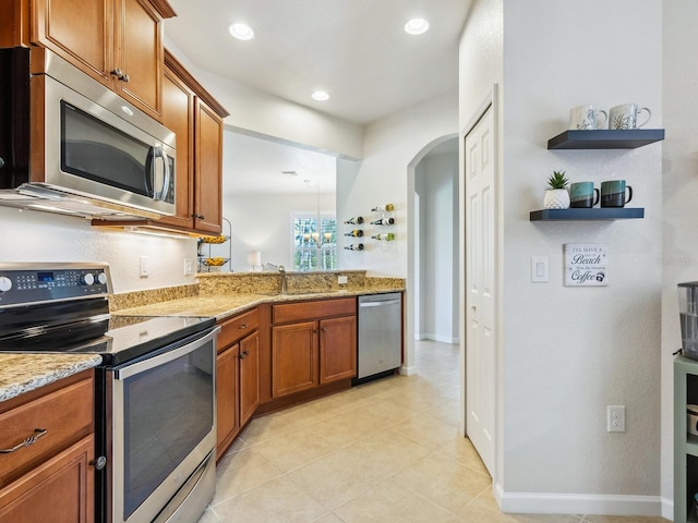 kitchen featuring light stone counters, sink, light tile patterned floors, and appliances with stainless steel finishes