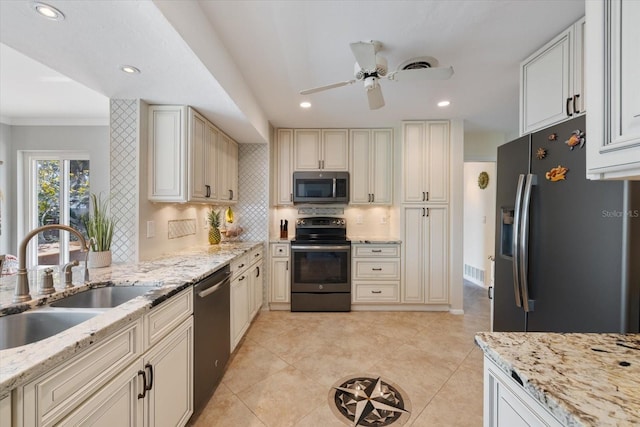 kitchen featuring light stone countertops, appliances with stainless steel finishes, backsplash, and a sink