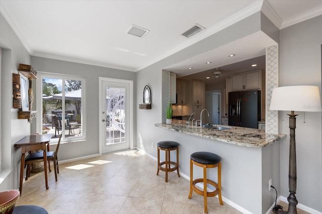 kitchen featuring crown molding, visible vents, black refrigerator with ice dispenser, and a sink