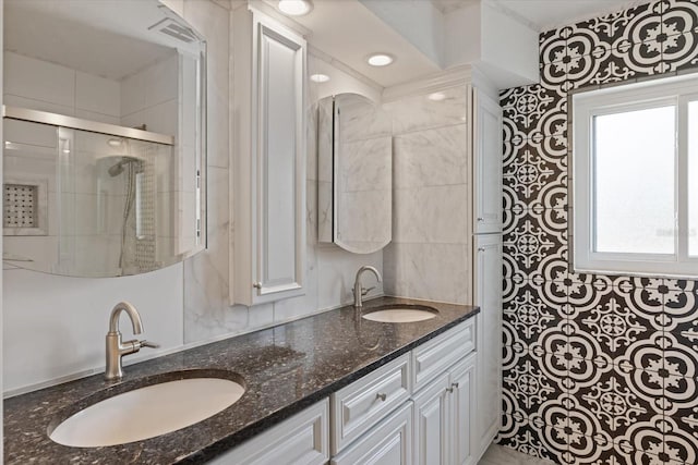 full bathroom featuring a tile shower, double vanity, a sink, and visible vents