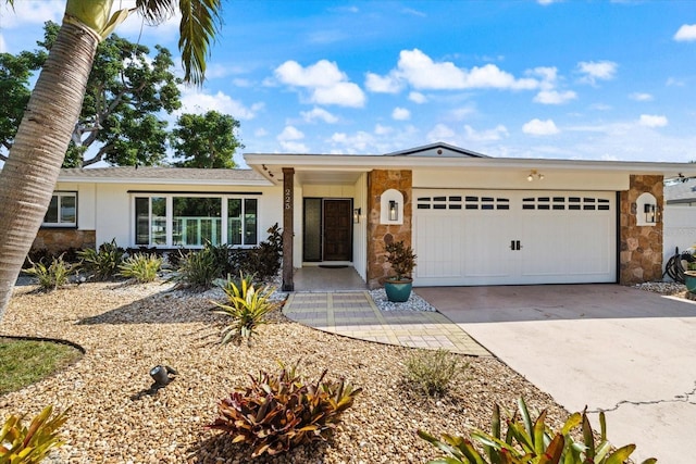 ranch-style house with concrete driveway, stone siding, an attached garage, and stucco siding