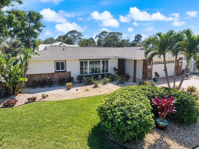 ranch-style house with a garage, concrete driveway, stone siding, board and batten siding, and a front yard