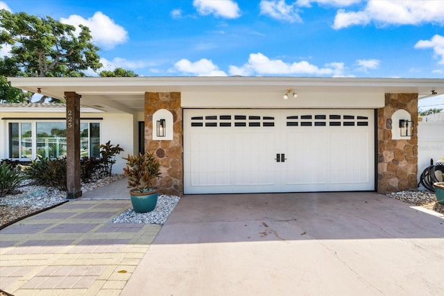 view of front facade featuring stone siding, concrete driveway, and an attached garage