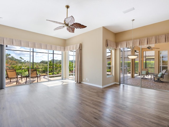 unfurnished living room featuring plenty of natural light, dark wood-type flooring, and ceiling fan