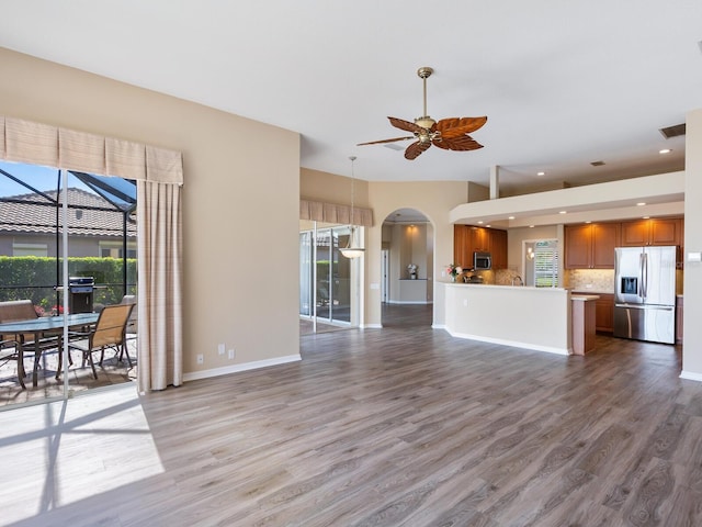 unfurnished living room with a wealth of natural light, wood-type flooring, and ceiling fan