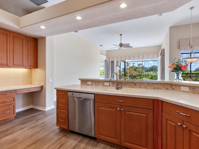 kitchen featuring sink, built in desk, hanging light fixtures, light hardwood / wood-style flooring, and stainless steel dishwasher