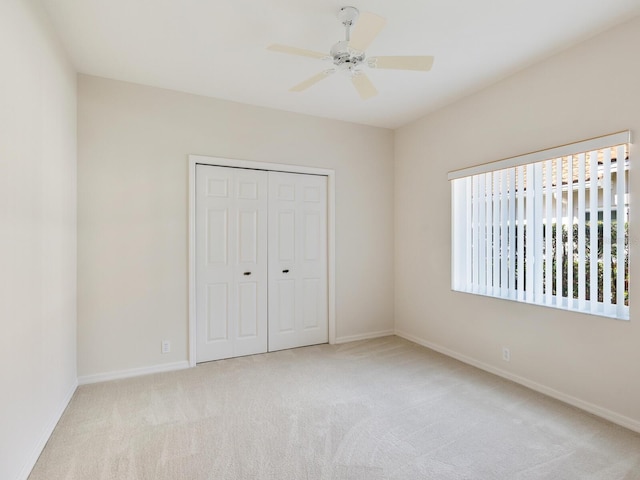 unfurnished bedroom featuring ceiling fan, a closet, and light carpet