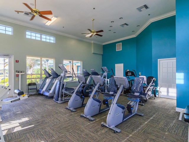 gym featuring crown molding, a towering ceiling, ceiling fan, and dark colored carpet