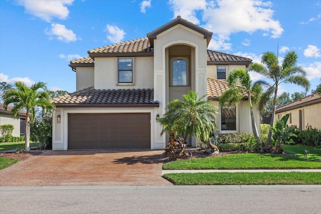 mediterranean / spanish house featuring a garage and a front lawn