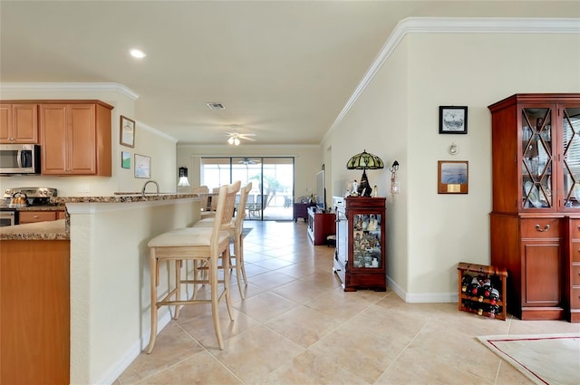 kitchen with crown molding, appliances with stainless steel finishes, and a breakfast bar