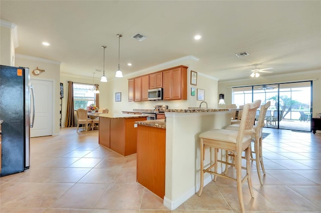 kitchen featuring ornamental molding, appliances with stainless steel finishes, pendant lighting, and light stone counters