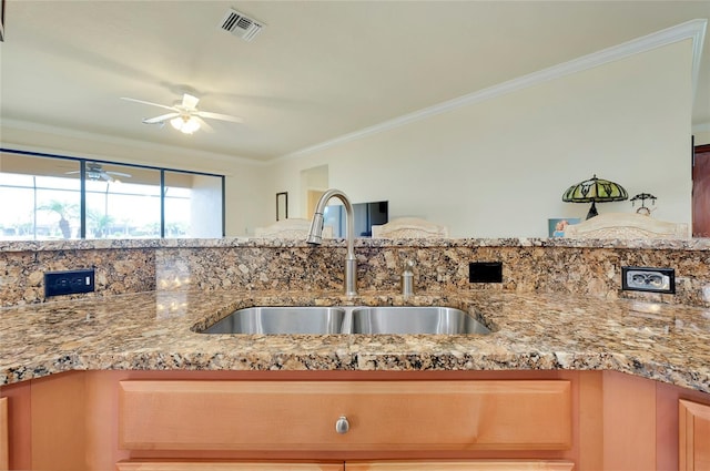 kitchen with ornamental molding, light stone countertops, and sink