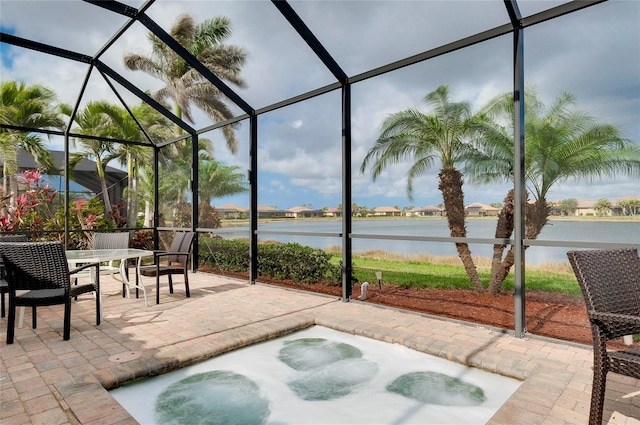 view of patio / terrace featuring a water view and glass enclosure