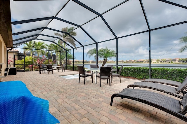 view of patio / terrace featuring a water view and glass enclosure