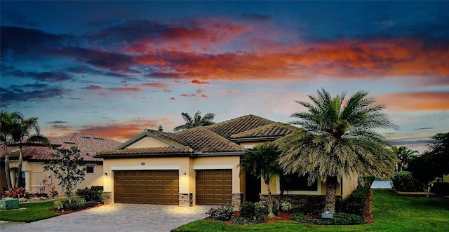 view of front of home featuring a garage, stone siding, a tiled roof, decorative driveway, and stucco siding