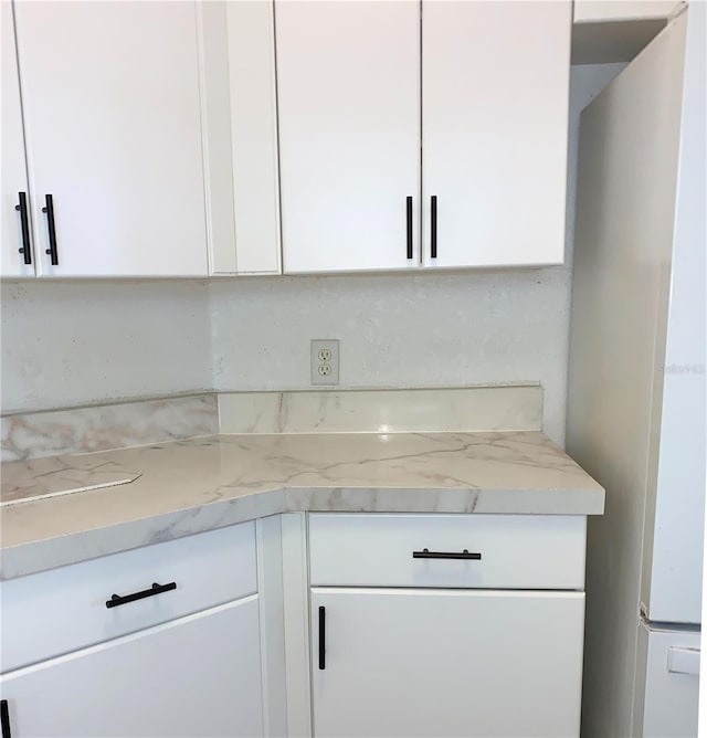 kitchen with white cabinetry and light stone countertops