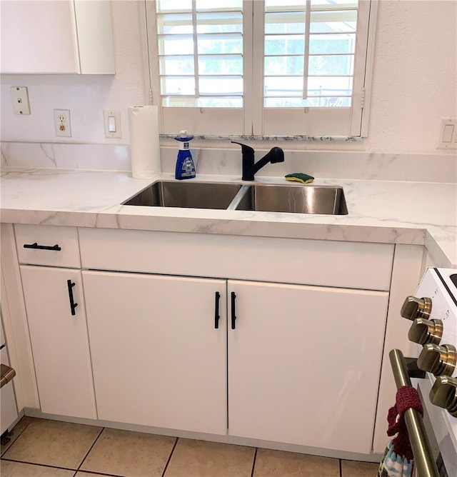 kitchen with plenty of natural light, white cabinets, stove, and a sink