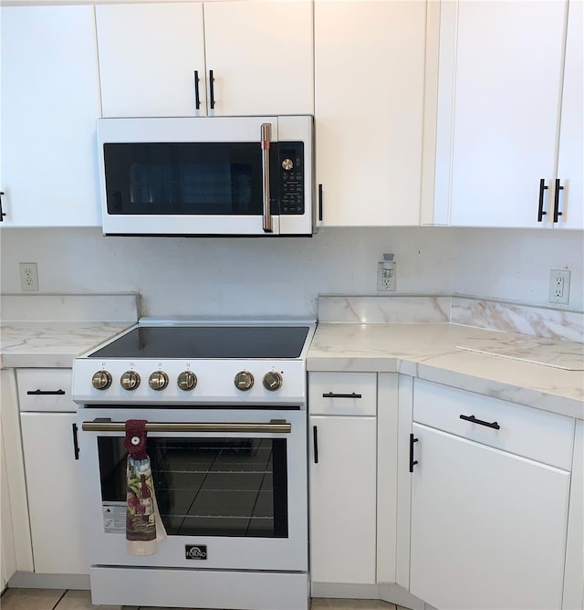 kitchen featuring white cabinets, light stone counters, and white appliances
