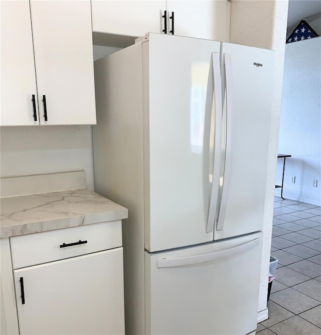 kitchen featuring light tile patterned flooring, white cabinets, and freestanding refrigerator