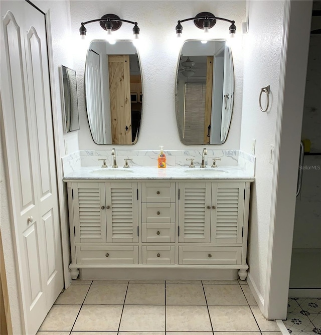 full bath featuring double vanity, a sink, and tile patterned flooring