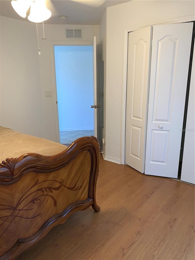 bedroom with a closet, visible vents, and wood finished floors