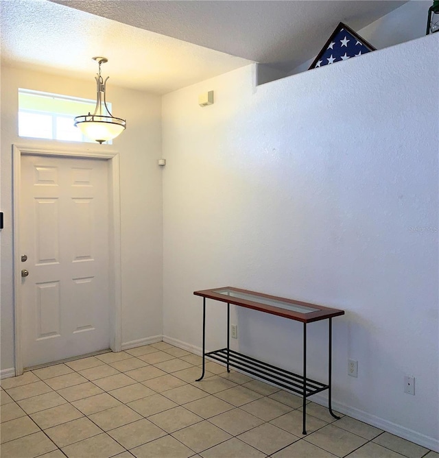 entrance foyer featuring baseboards, a textured ceiling, and light tile patterned floors