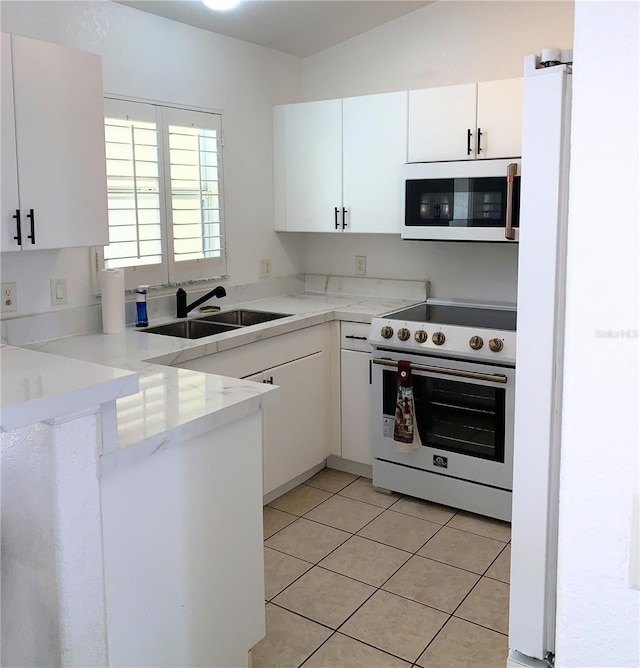 kitchen featuring light tile patterned flooring, light countertops, a sink, white appliances, and white cabinets