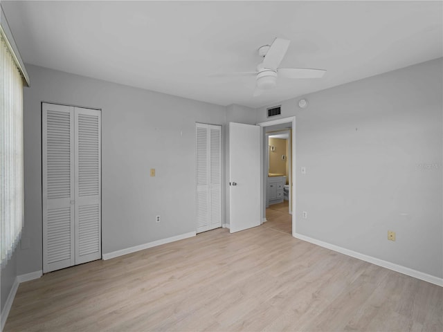 unfurnished bedroom with ceiling fan, light hardwood / wood-style flooring, and two closets