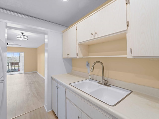 kitchen with white cabinetry, sink, ceiling fan, and light hardwood / wood-style flooring