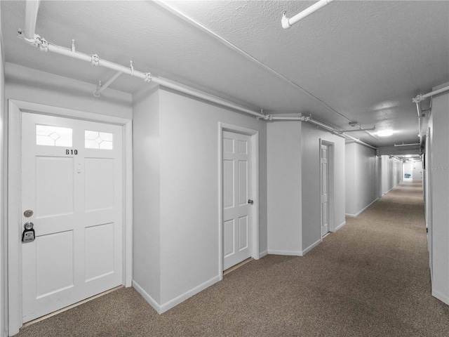 basement featuring a textured ceiling and dark colored carpet