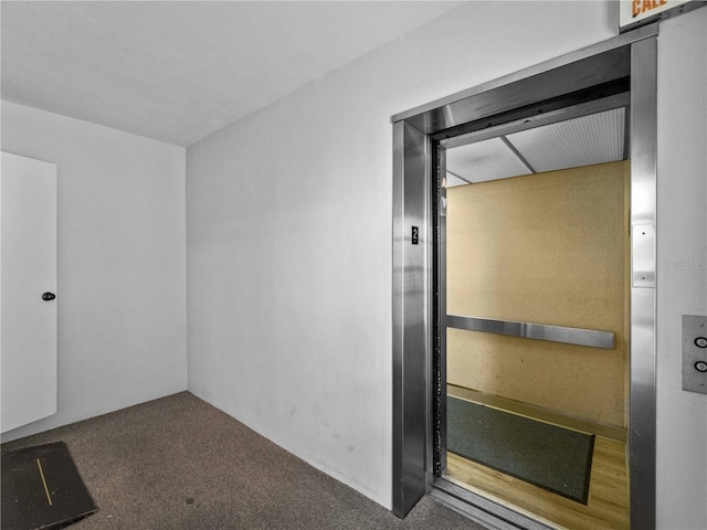 unfurnished room with elevator and dark colored carpet