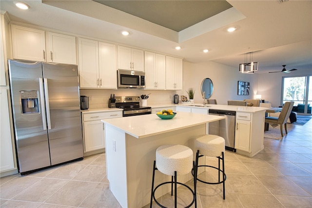 kitchen featuring a peninsula, appliances with stainless steel finishes, a tray ceiling, and light tile patterned flooring